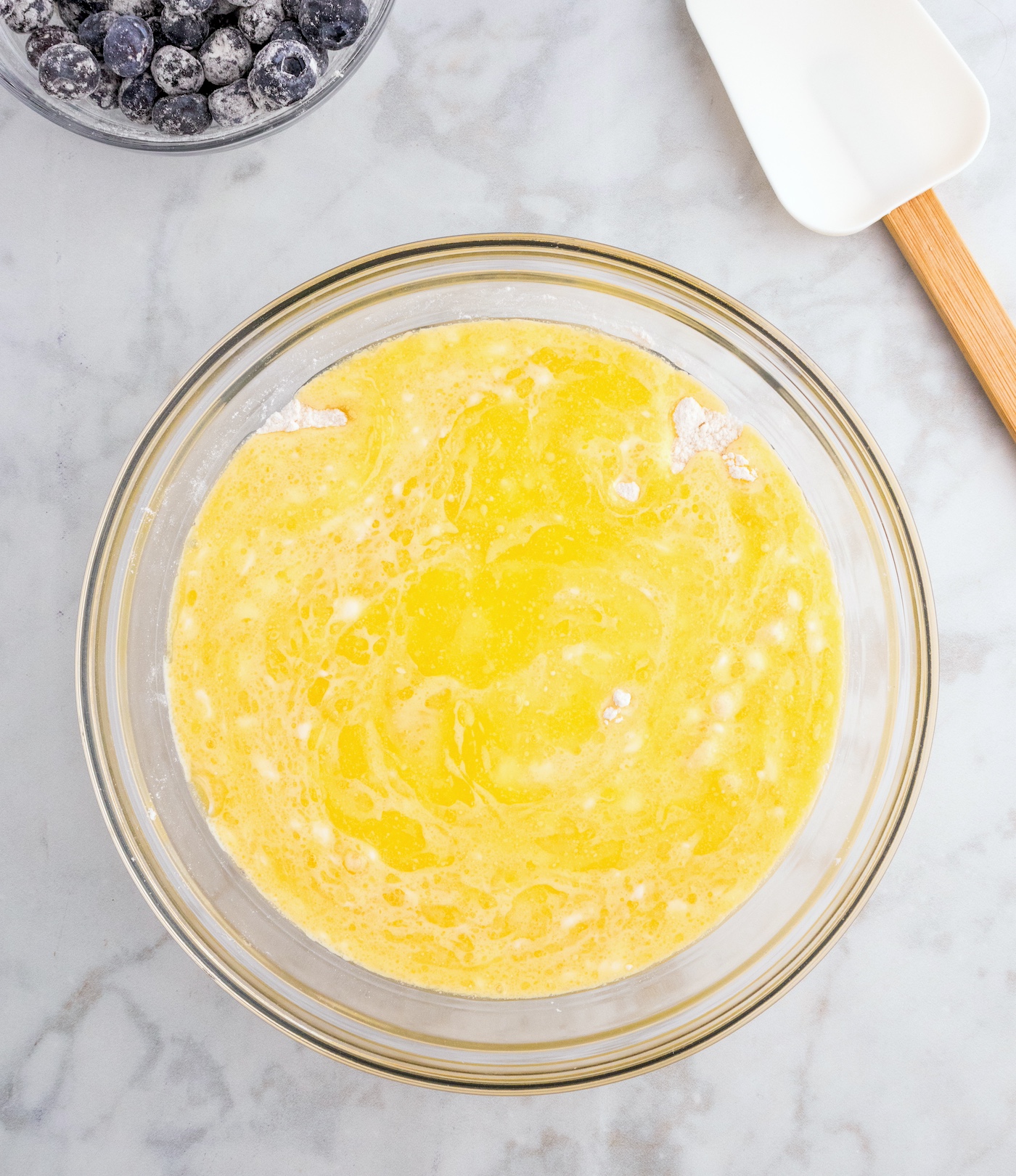 Pouring the wet lemon muffin ingredients into the dry