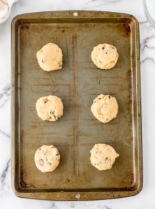 chocolate chip cookie dough balls placed on a cookie sheet