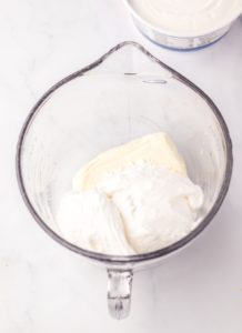 cream cheese, marshmallow cream, and powdered sugar in a glass bowl