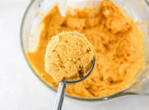 scooping pumpkin whoopie pie batter onto a baking sheet