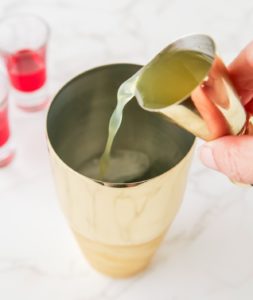 pouring pineapple juice into a shaker