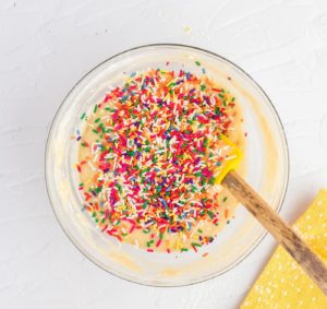 folding rainbow sprinkles into the batter