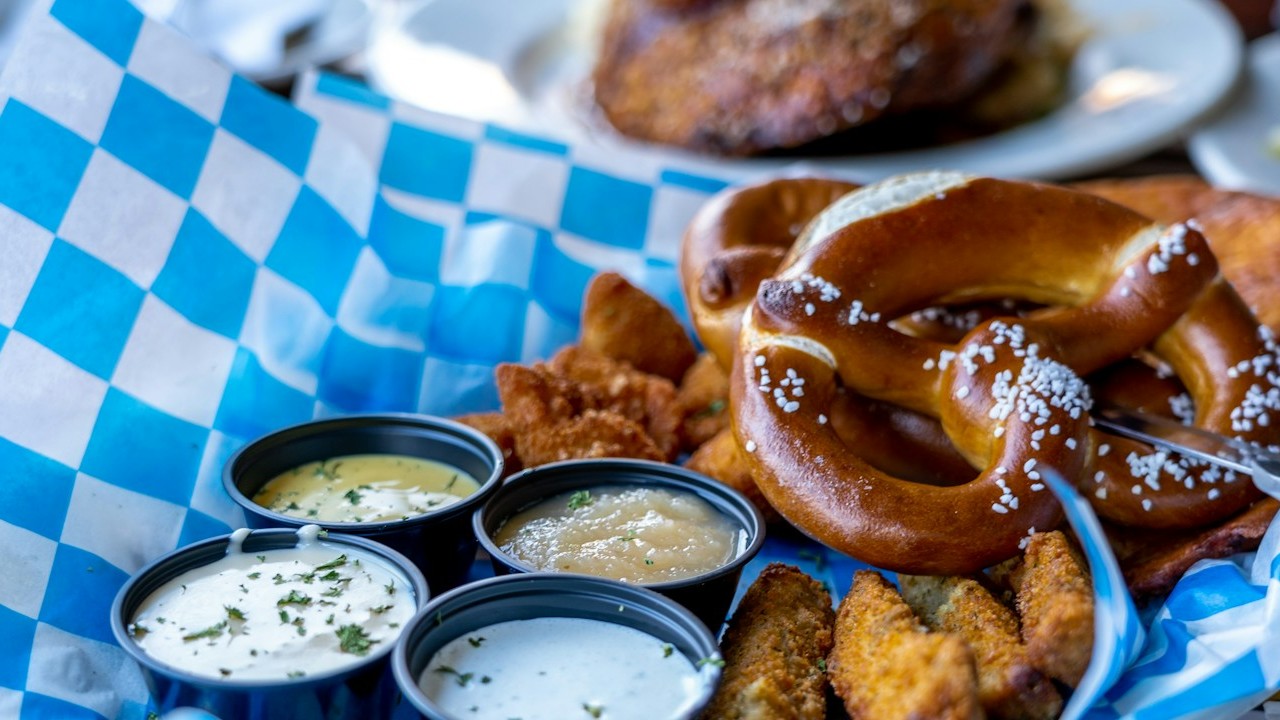 Soft pretzels with small cups of warm cheese sauce