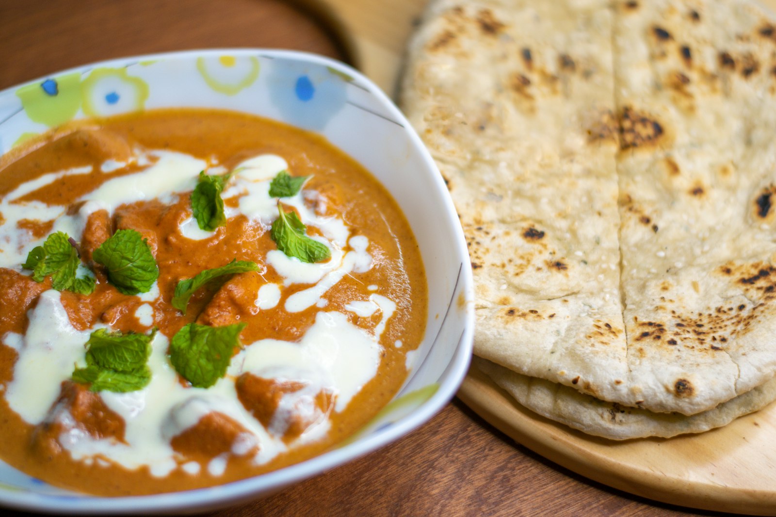 Slow cooker dinners: creamy butter chicken with fresh cilantro next to warm naan bread