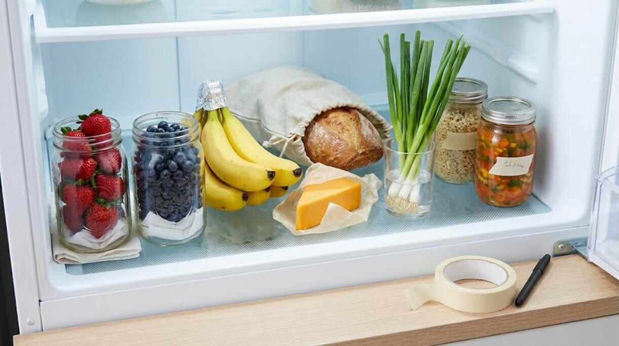 Tidy refrigerator shelf with labeled jars, berries, cheese and bread