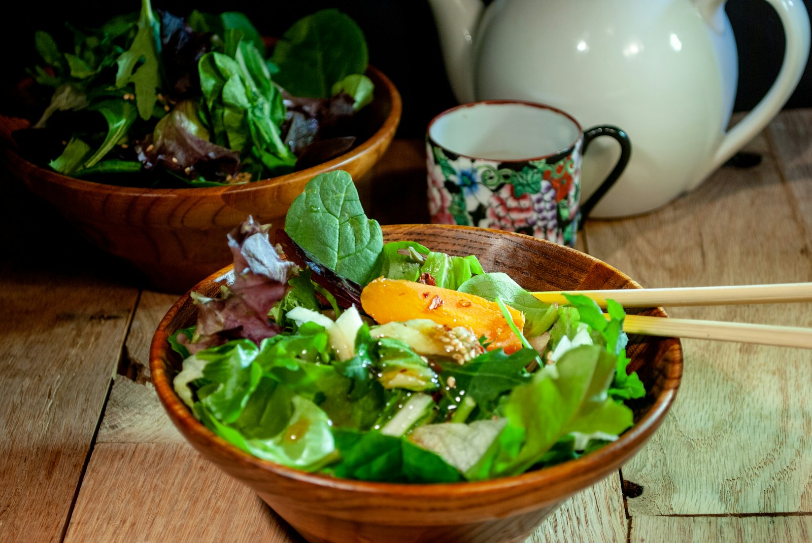 Fresh green salad with chopsticks and tea