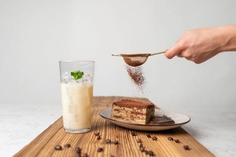 Cocoa powder being dusted over a slice of tiramisu