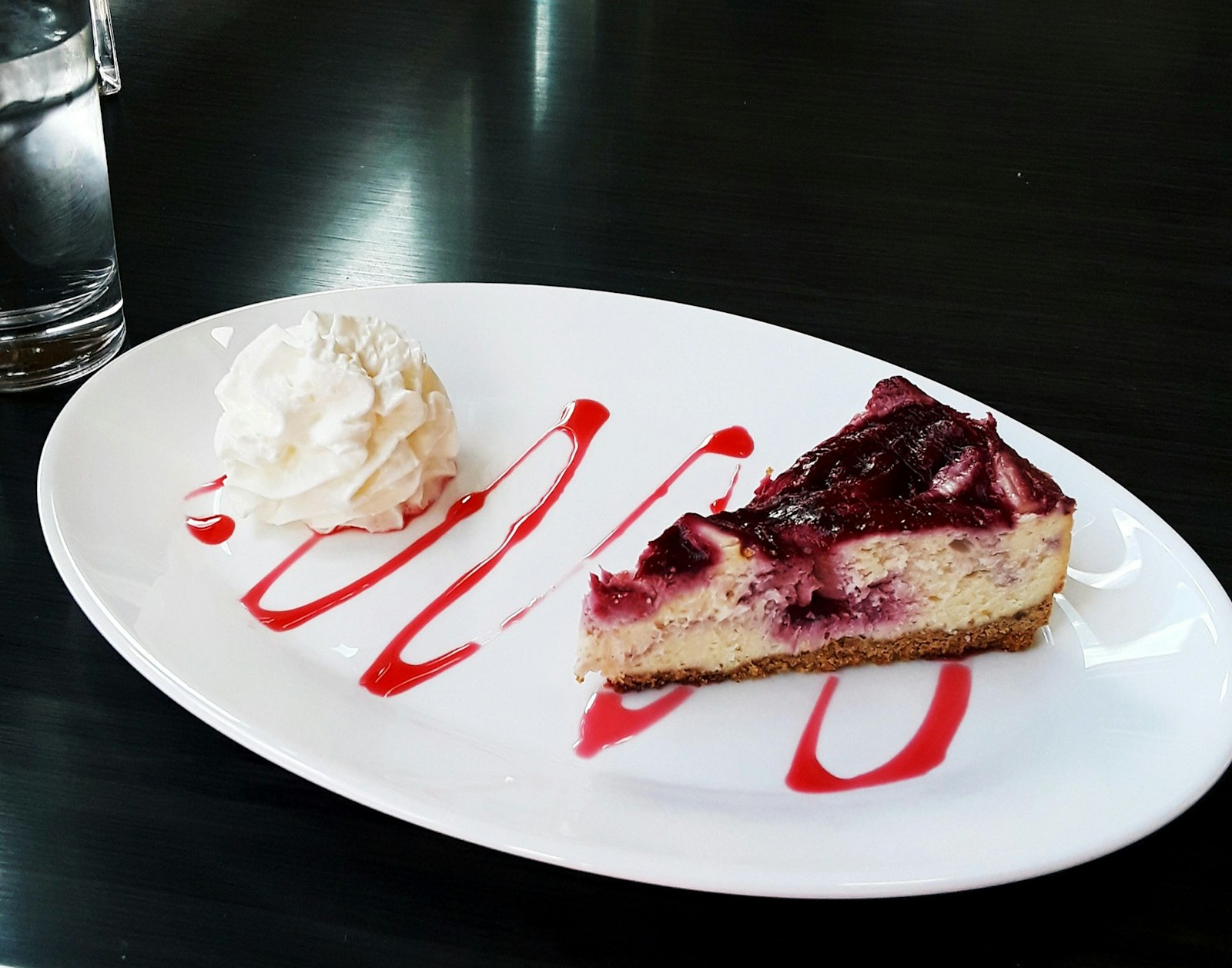 Slice of creamy cheesecake with red berry sauce