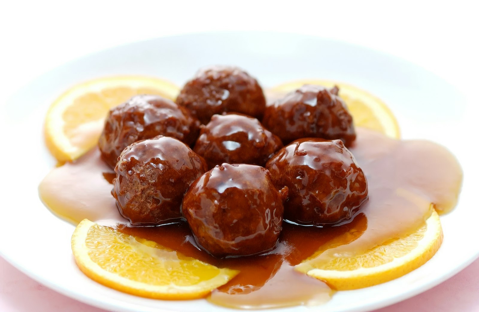 Glazed cranberry meatballs with orange slices on a plate