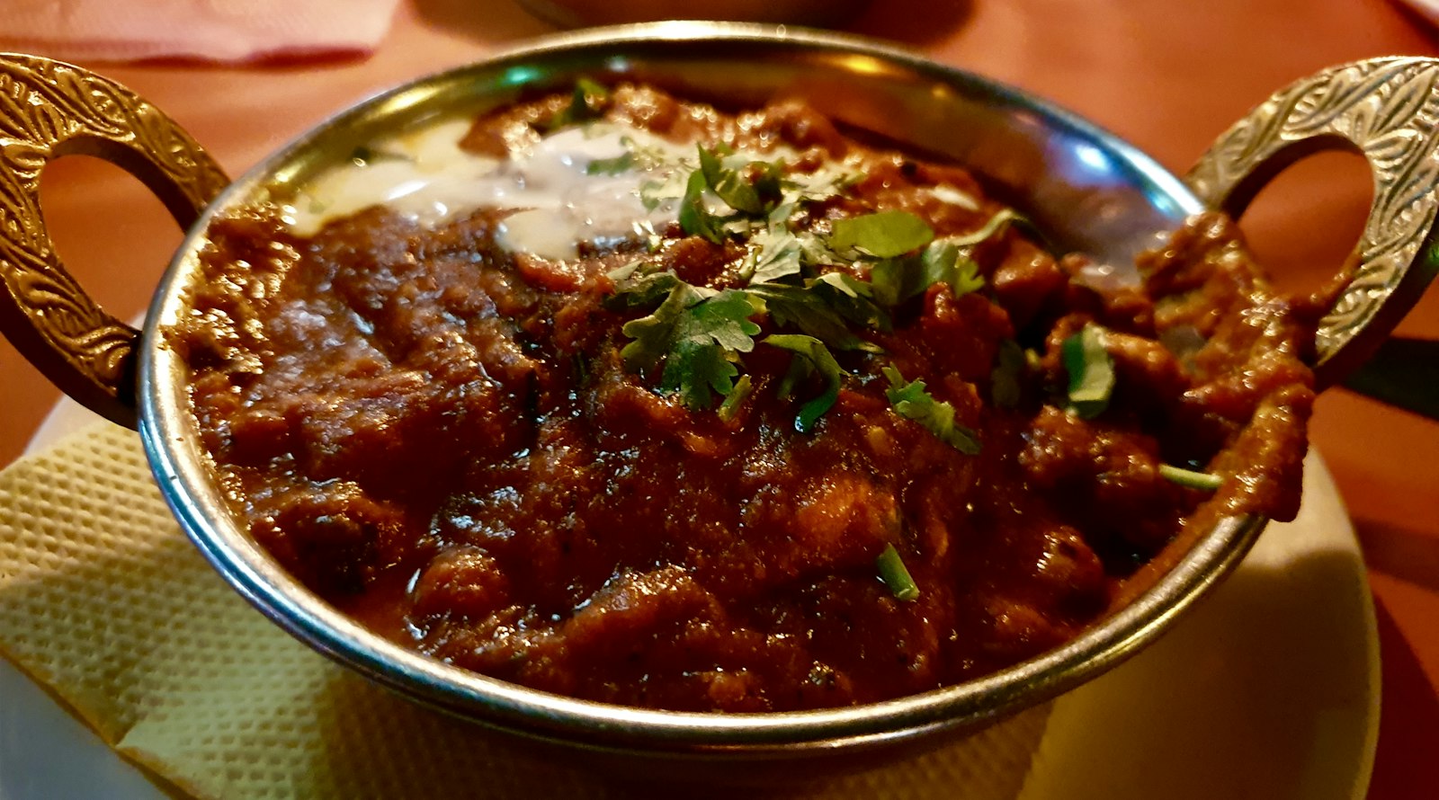 Rich red curry with tender meat in a copper pot