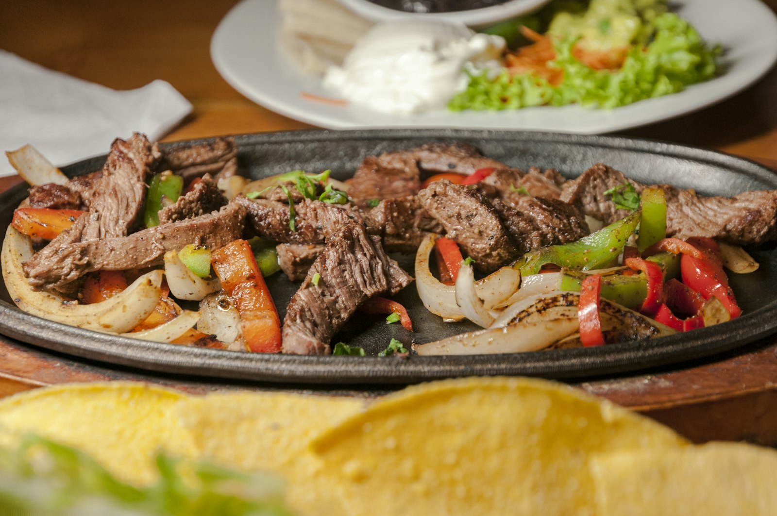 Sizzling beef fajitas with peppers and onions on a cast iron platter
