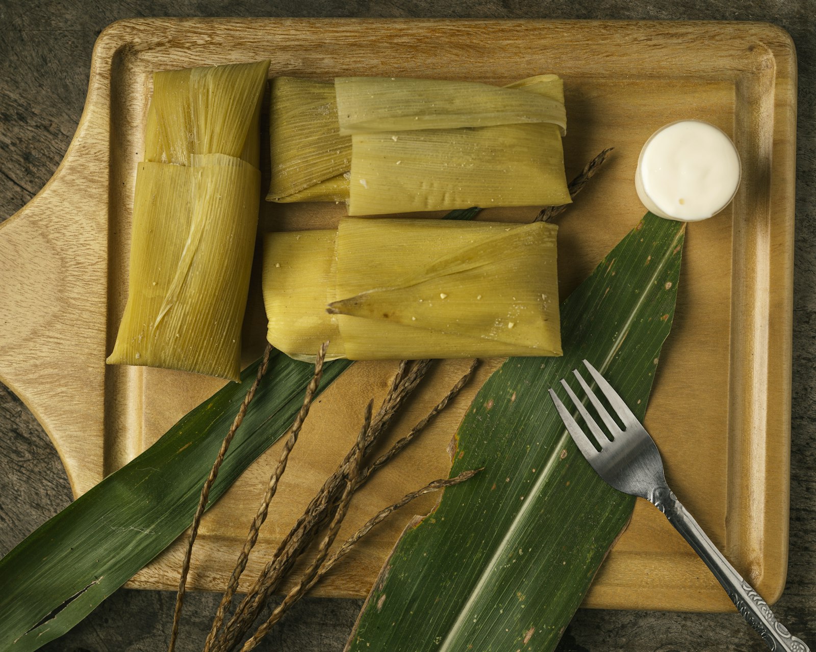 Tamales wrapped in corn husks on a wooden board