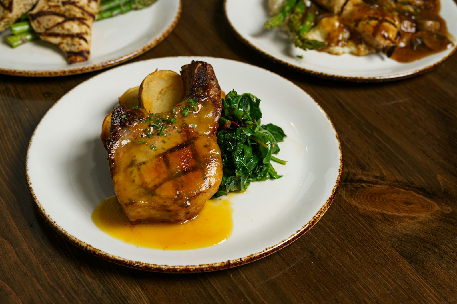 Honey garlic pork chop with greens on a white plate