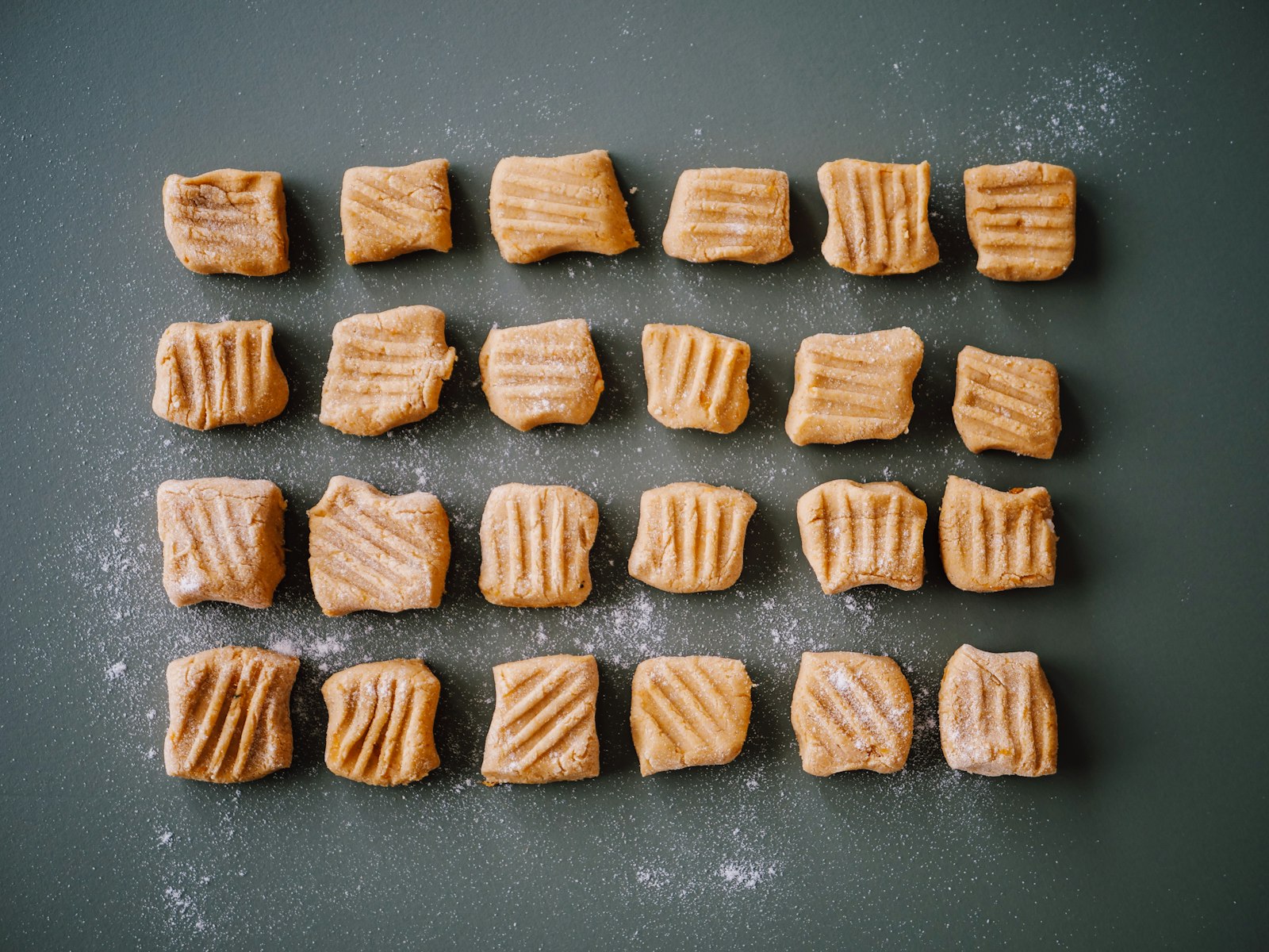 Homemade gnocchi pieces on a gray tray