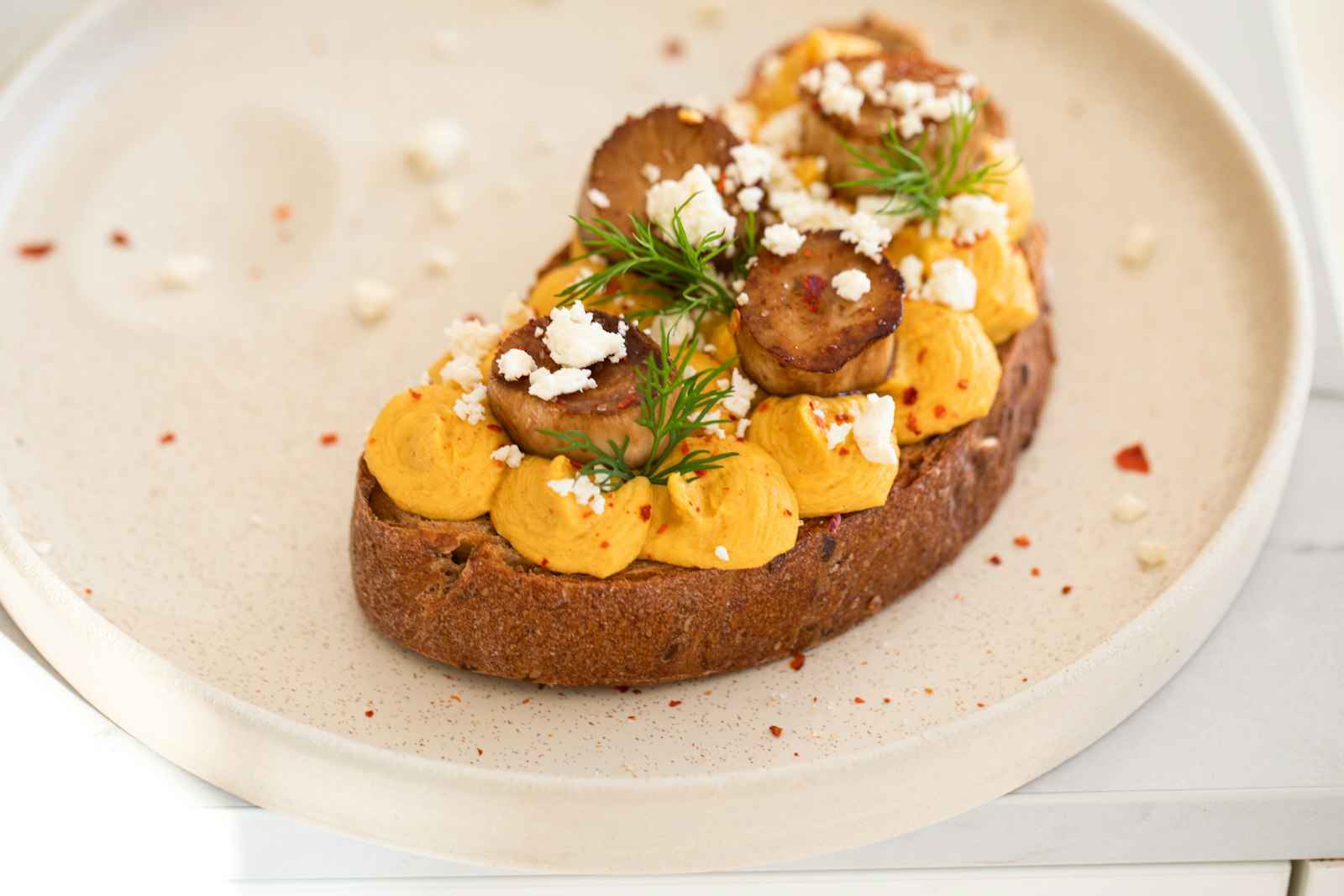 Toast topped with a creamy orange mash, seeds and herbs