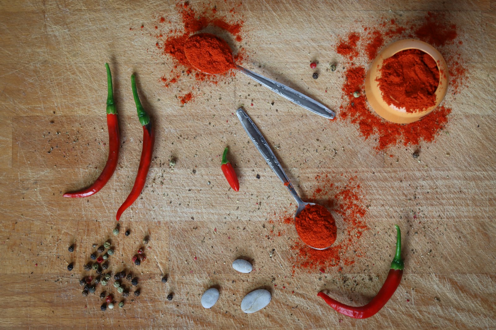 Dried red peppers and a ground spice blend on a wooden table