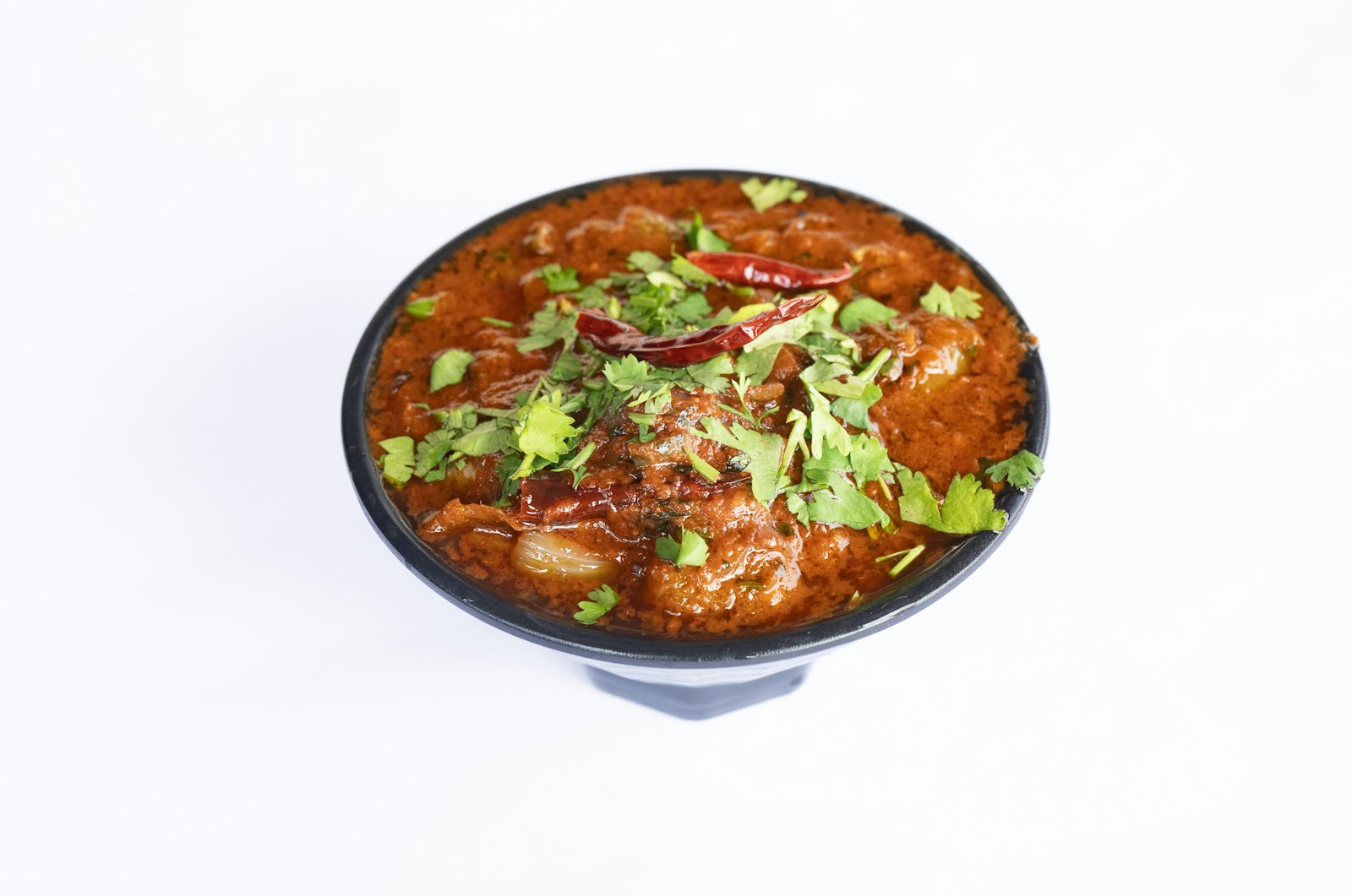 Lean ground turkey and bean stew in a black bowl topped with fresh herbs