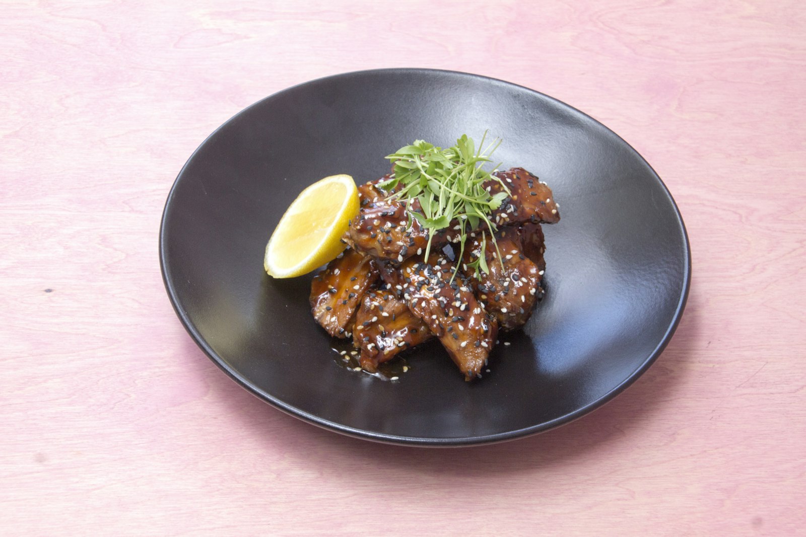 Sticky honey garlic chicken on a dark plate