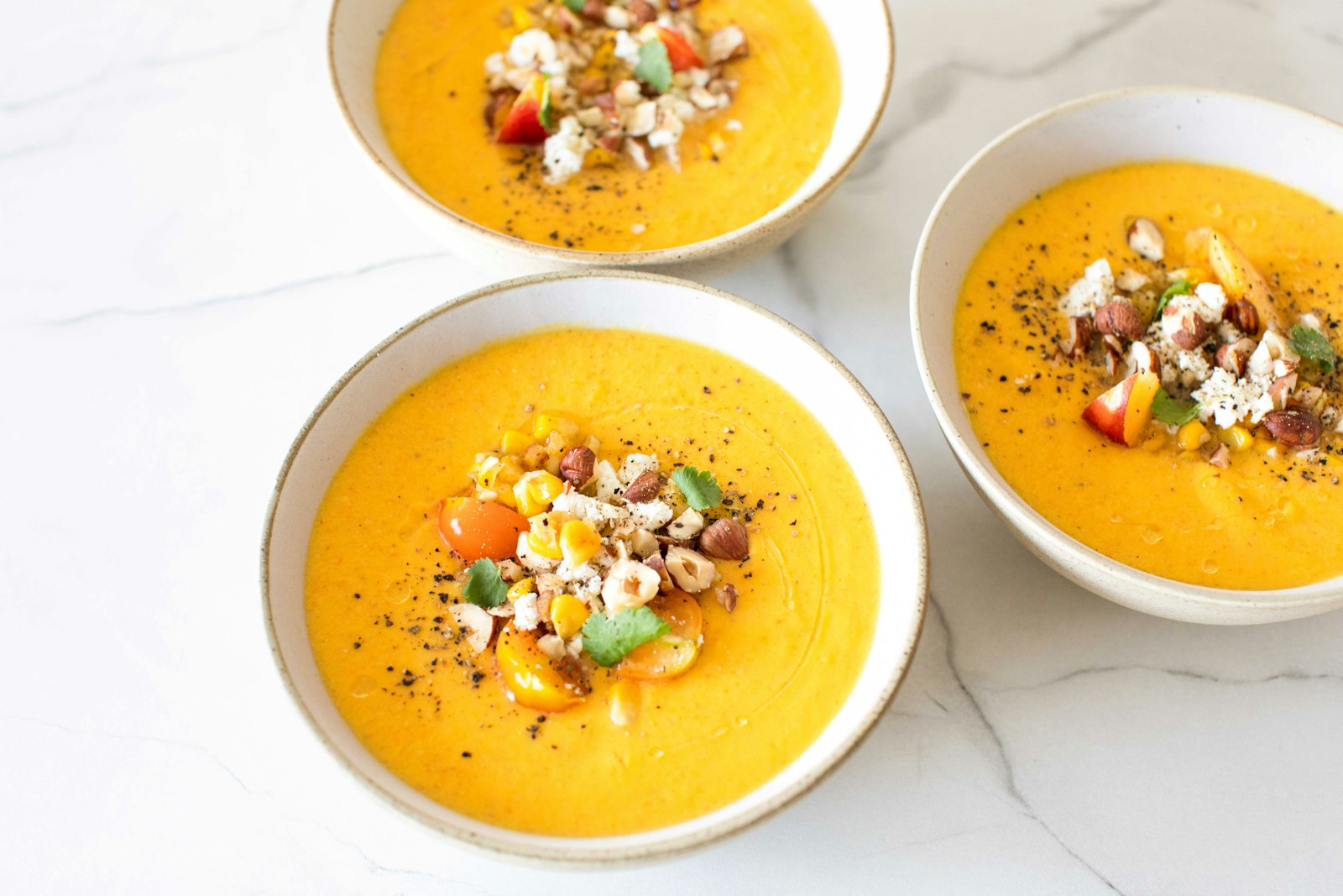 Bowls of smooth sweet potato soup with crunchy toppings