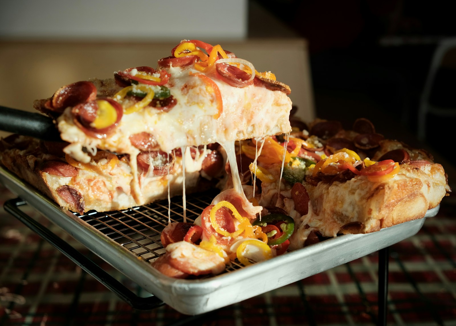 Cheesy homemade sheet pan pizza slice being lifted