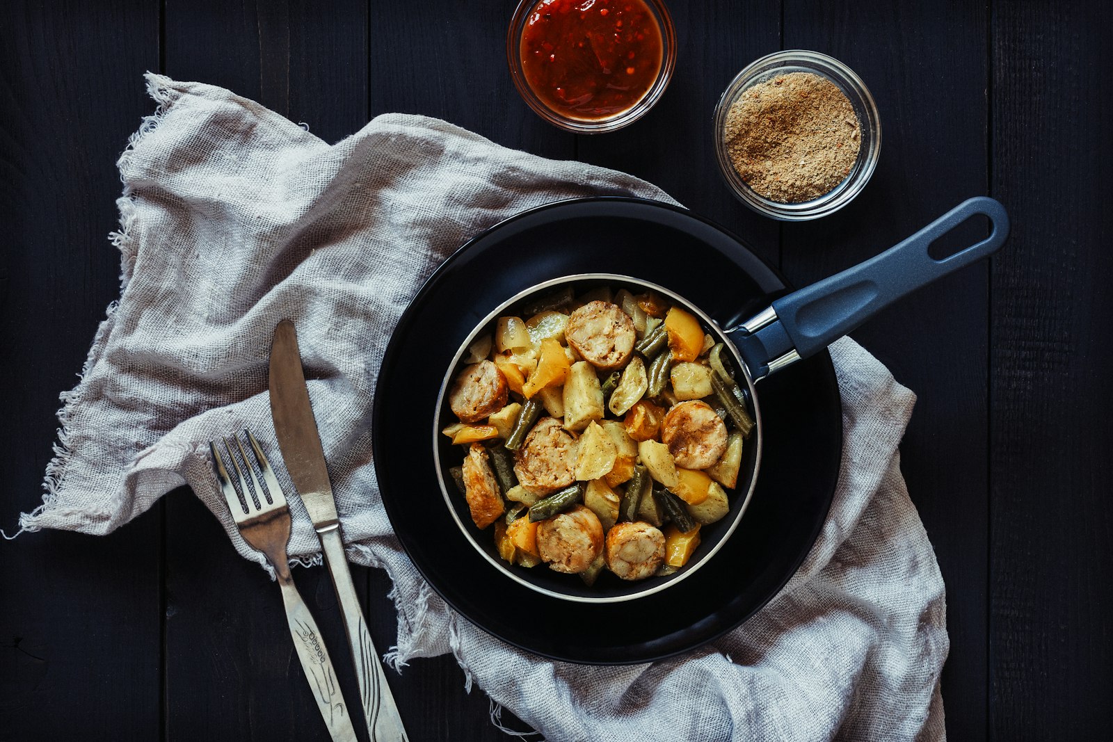 Smoked sausage with roasted potatoes and vegetables in a pan