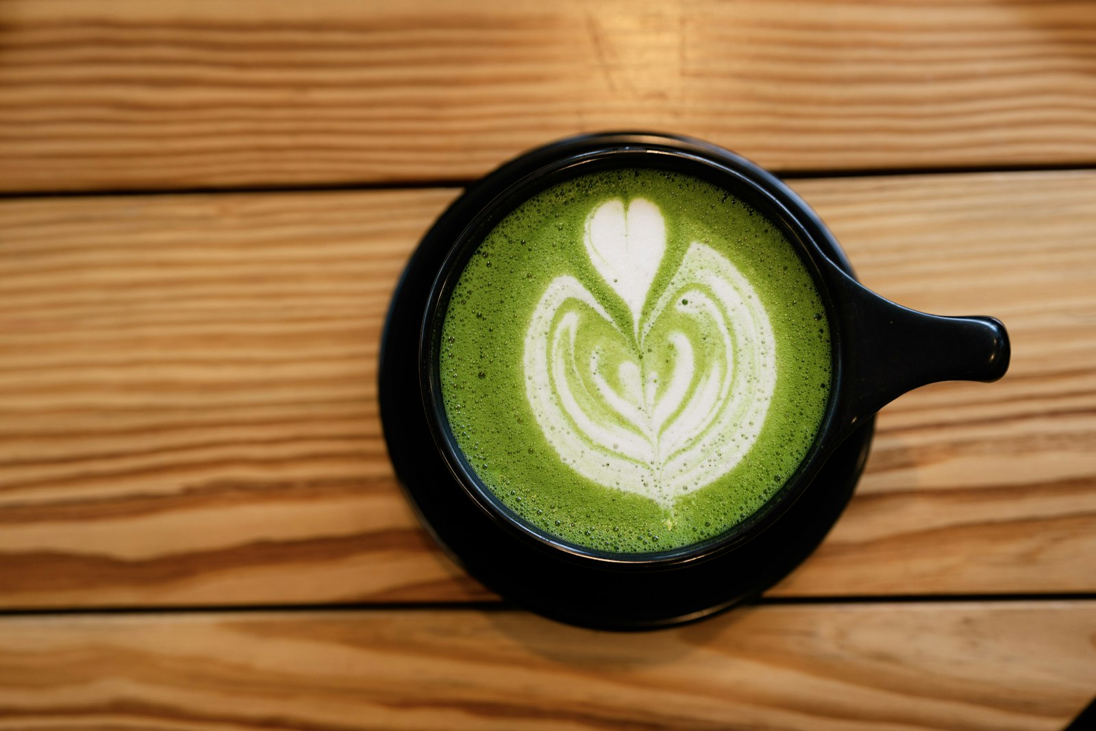 Matcha latte with latte art in a black cup