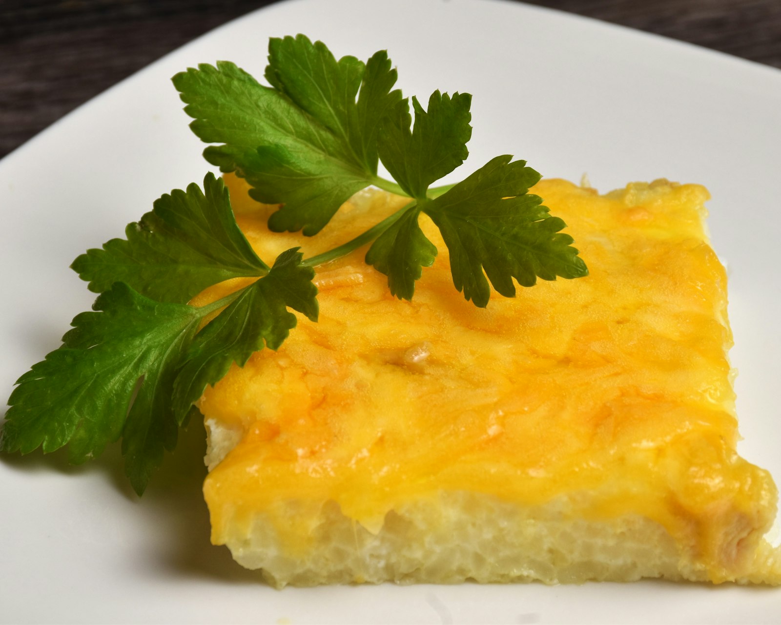 Square of baked casserole with parsley