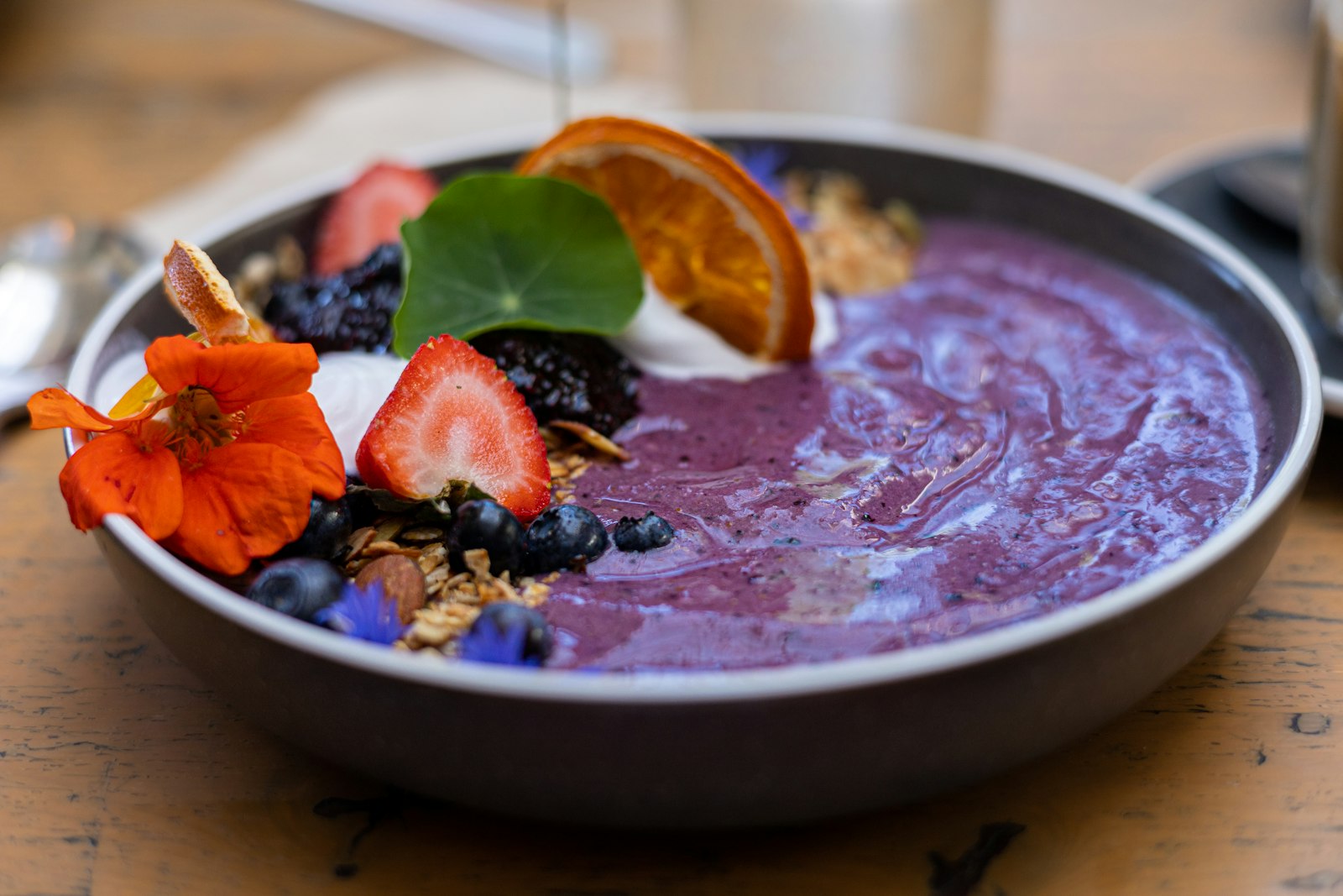 Purple acai bowl with fruit and flowers