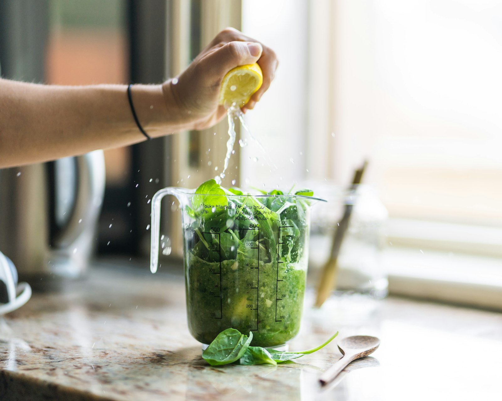 Kale pineapple drink with lemon being squeezed