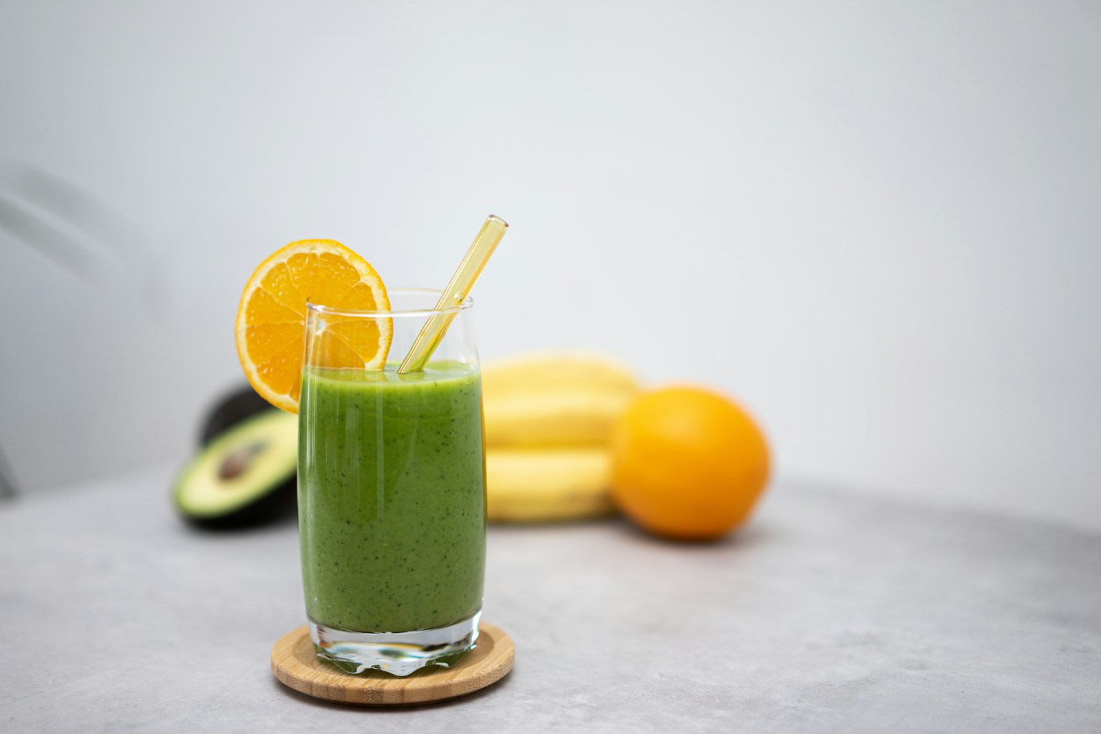 Spinach orange drink with an orange slice and a straw