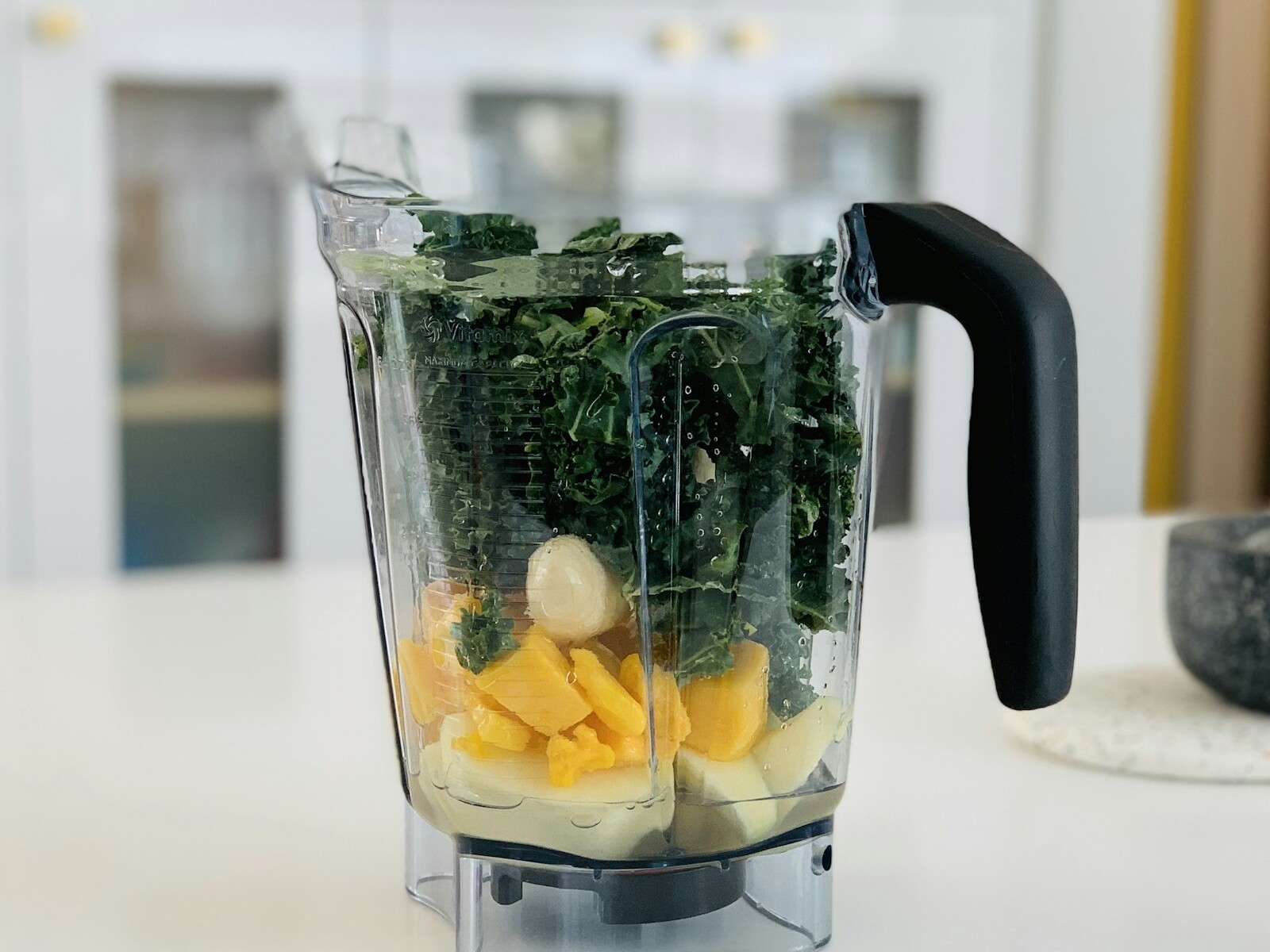 Blender filled with greens and fruit for a smoothie