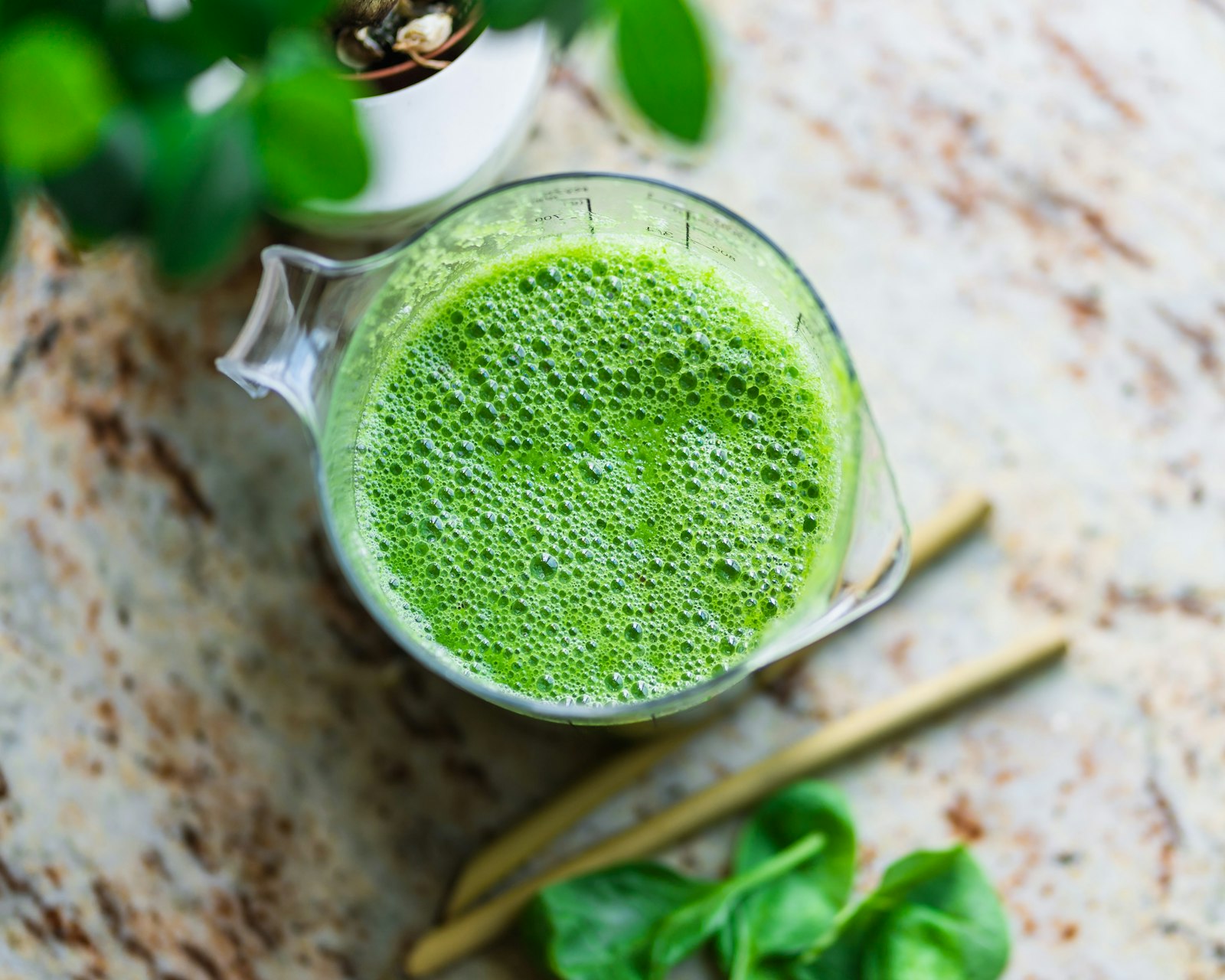 Pitcher of a blended spinach drink with straws