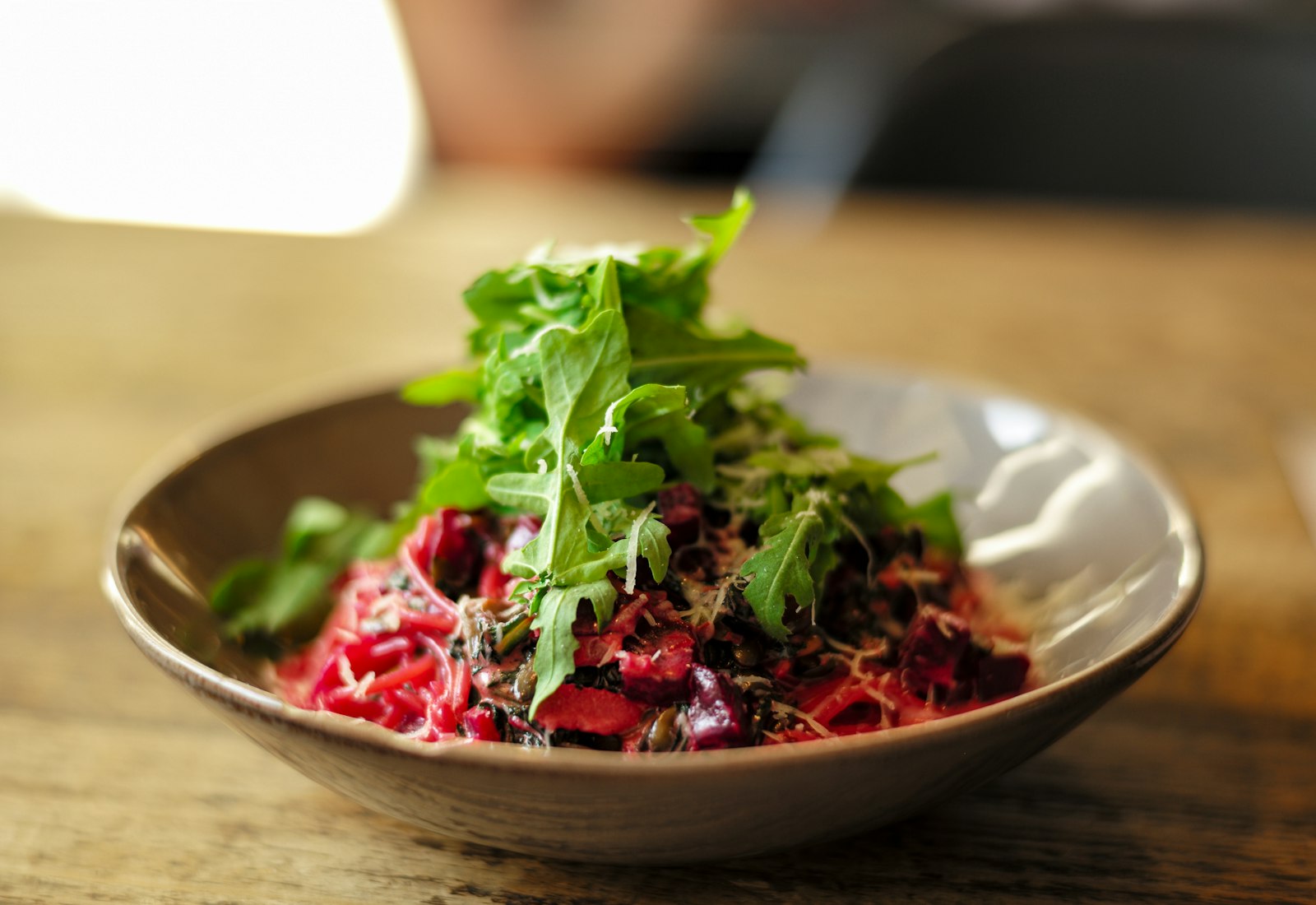 Arugula on roasted beets in a brown ceramic dish