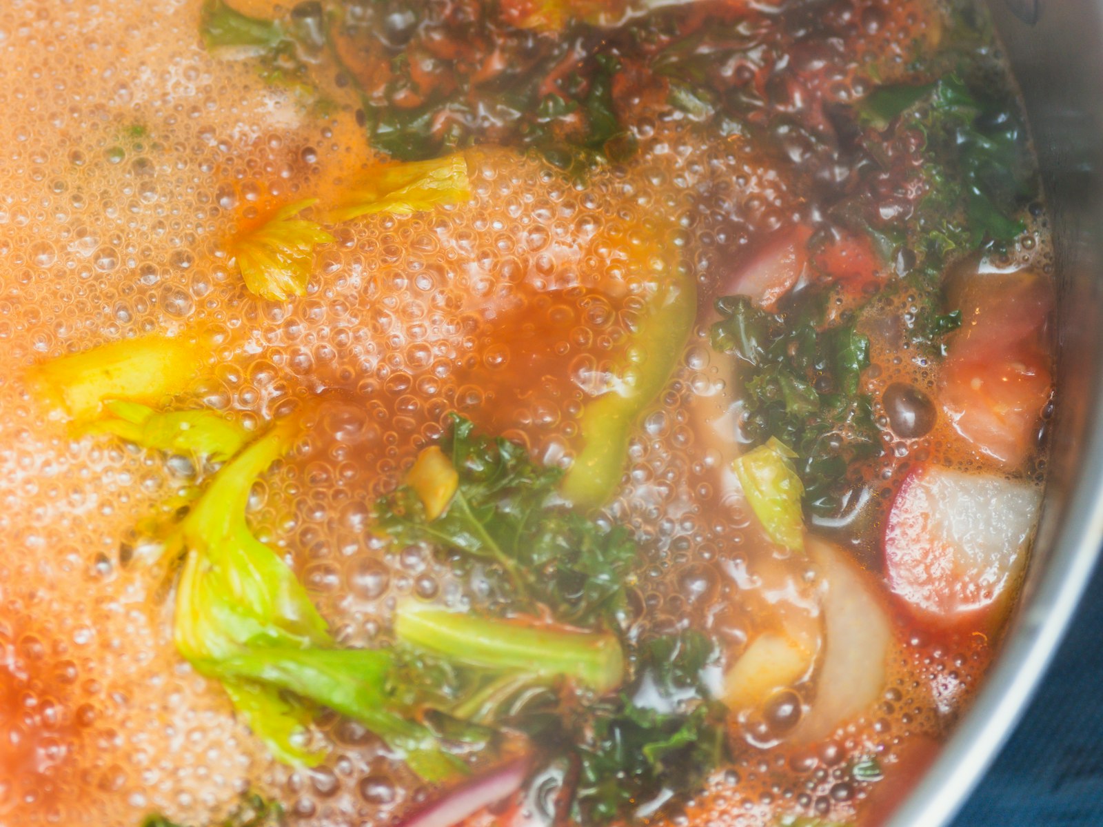 Tuscan soup with kale, beans and vegetables simmering in a pot