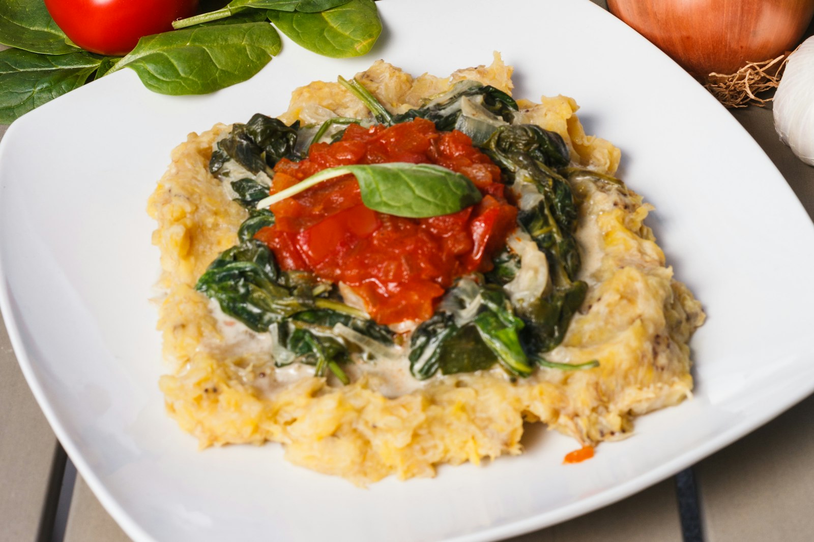 Creamy polenta topped with leafy greens and tomato sauce