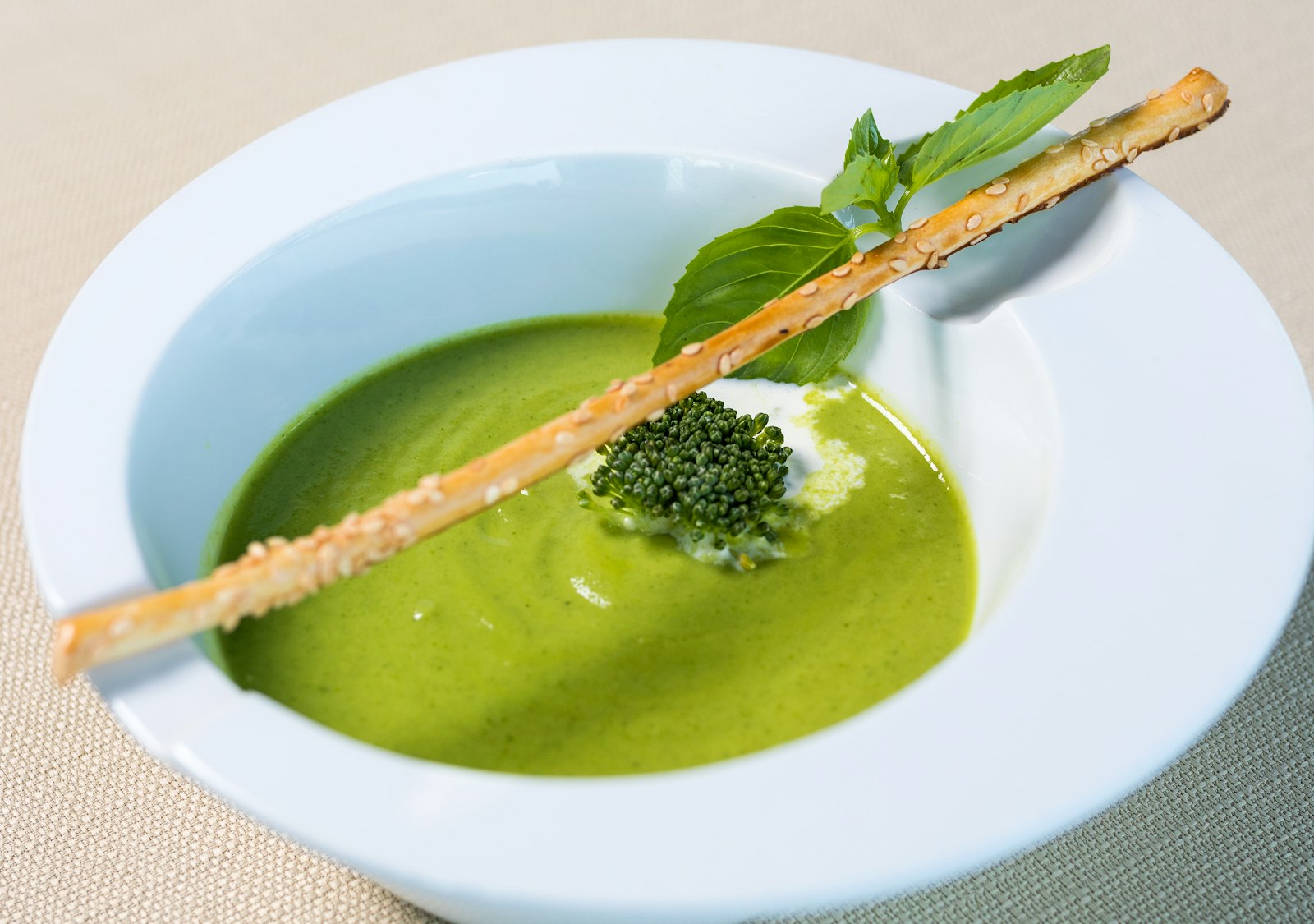 Creamy green spinach soup with a breadstick