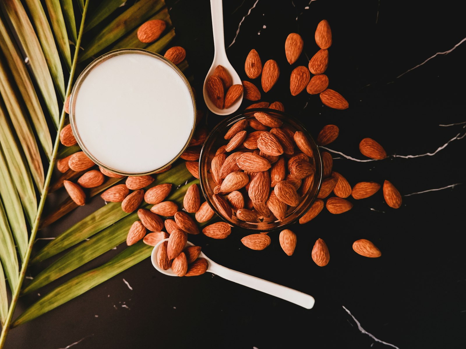 Homemade almond milk with whole almonds on a dark table