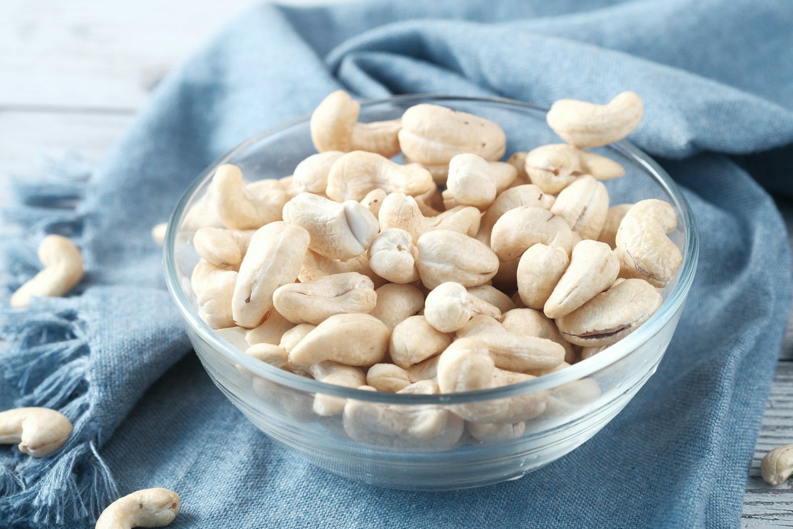 Bowl of raw cashews on a blue cloth