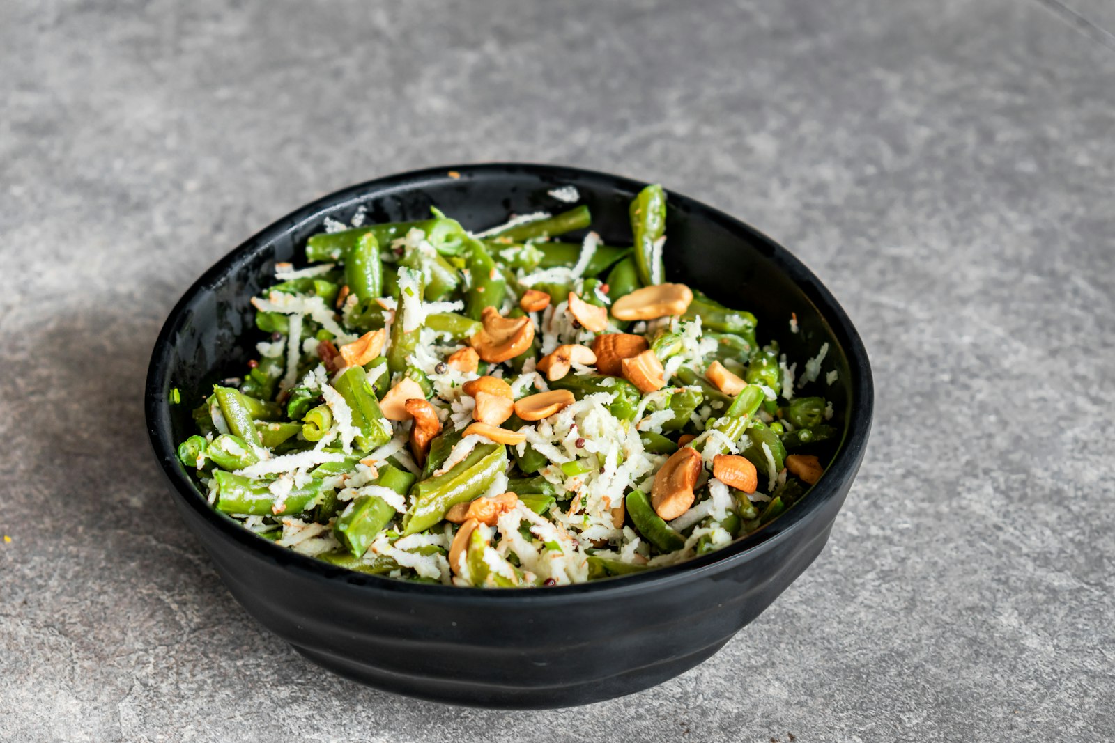 Green beans with toasted almonds and parmesan in a black dish