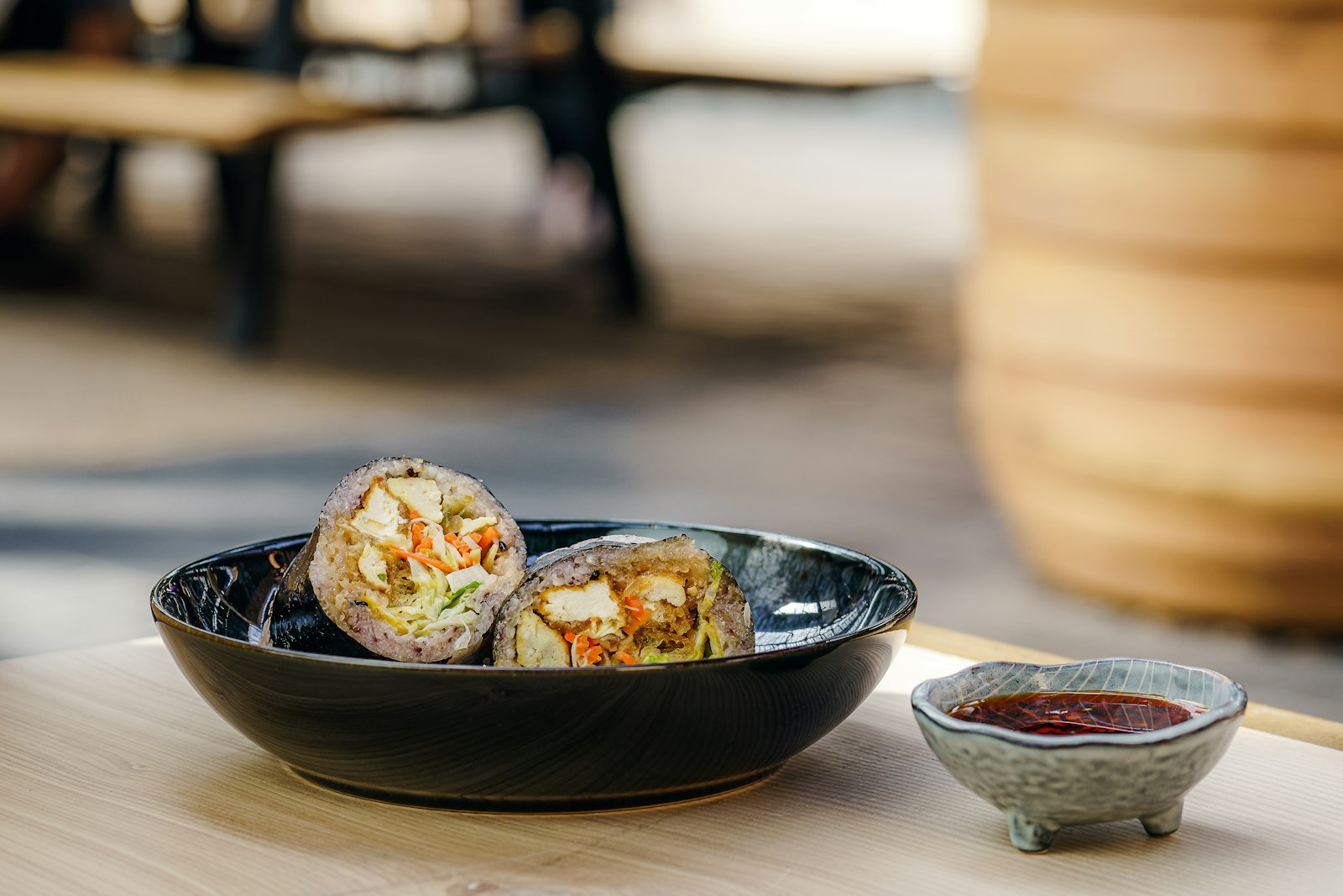 Chicken and vegetable wraps cut in half in a black bowl