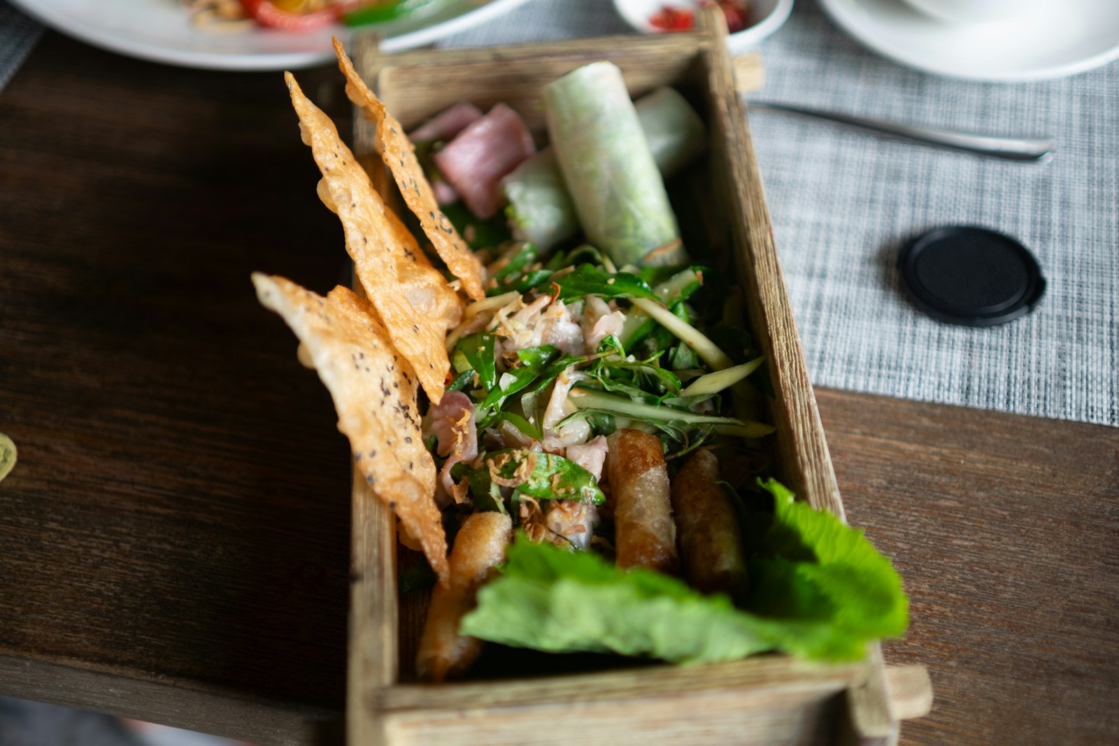 Fresh spring rolls with herbs and crispy wonton chips in a wooden tray