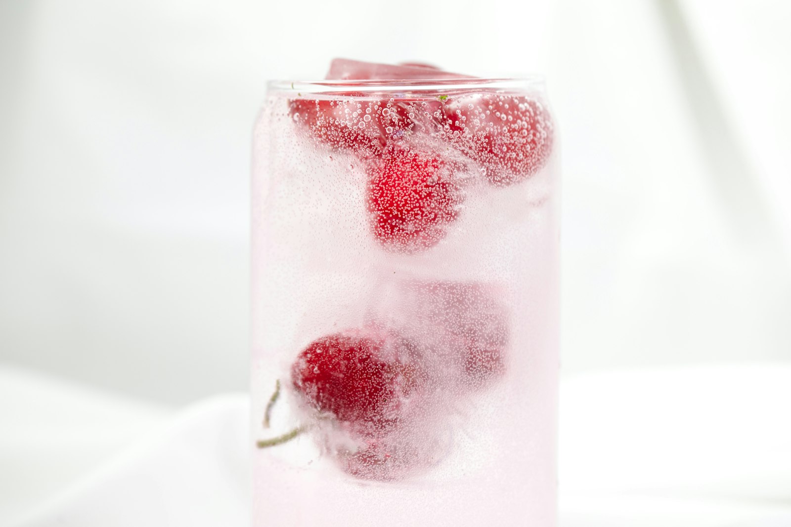 Frozen raspberries in a glass of sparkling water