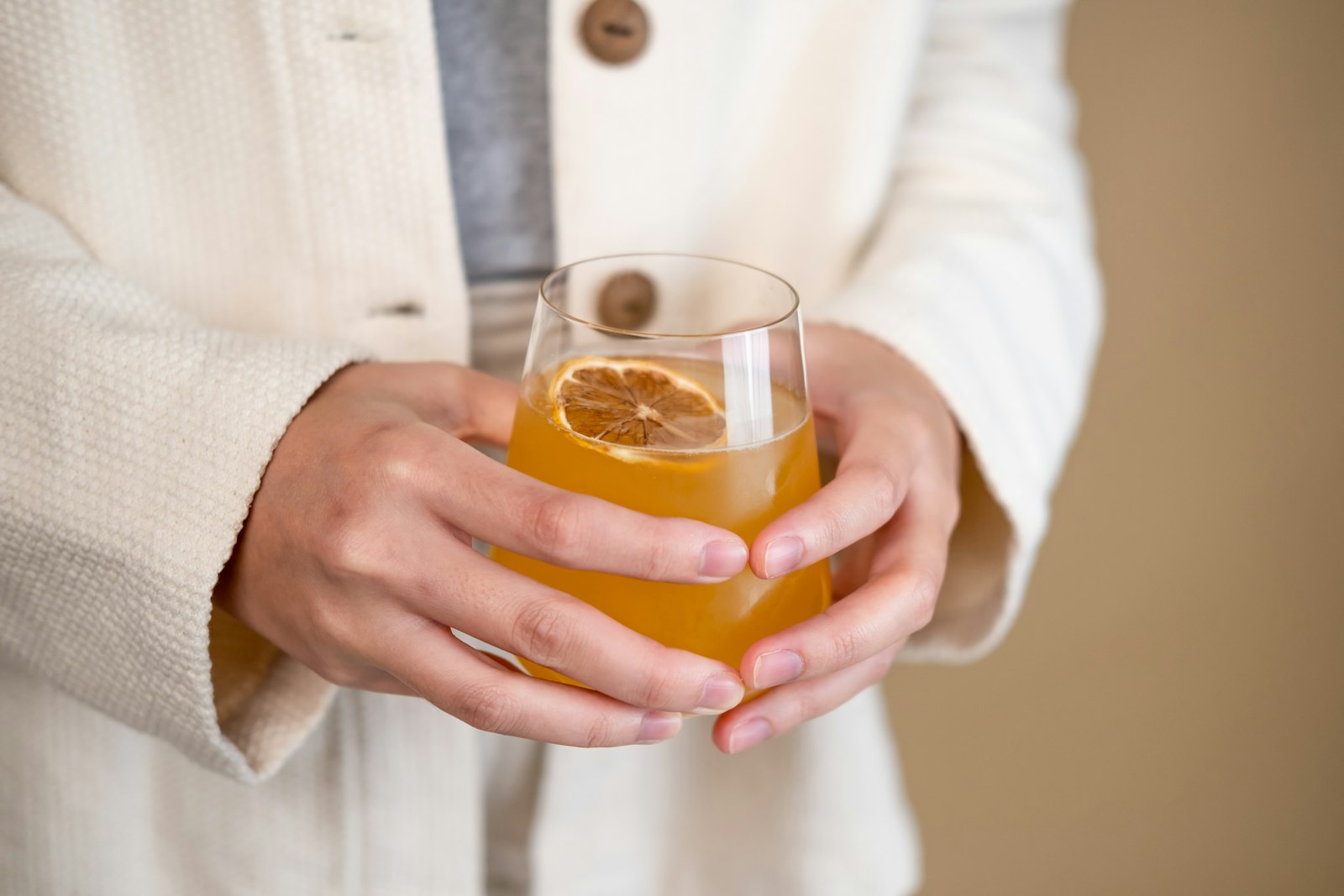 Hands holding a glass of apple shrub soda