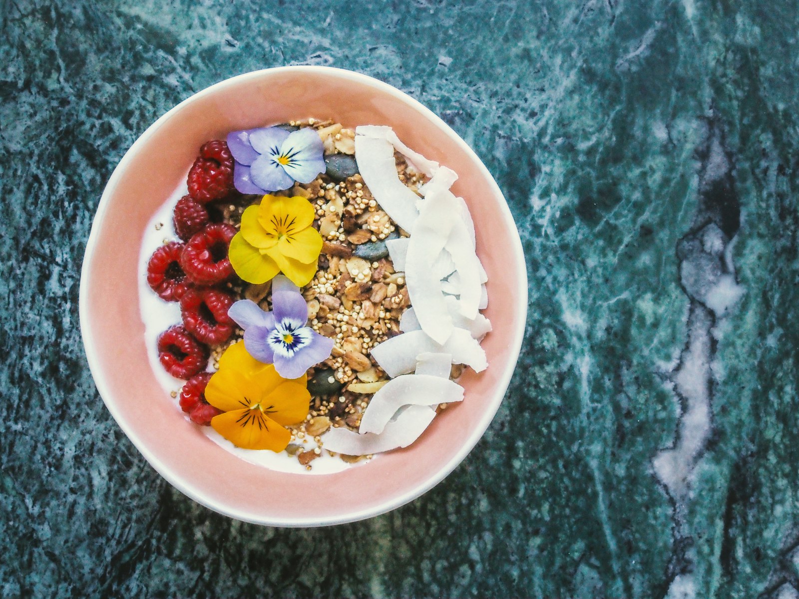 Acai topped with granola, raspberries, coconut and edible flowers