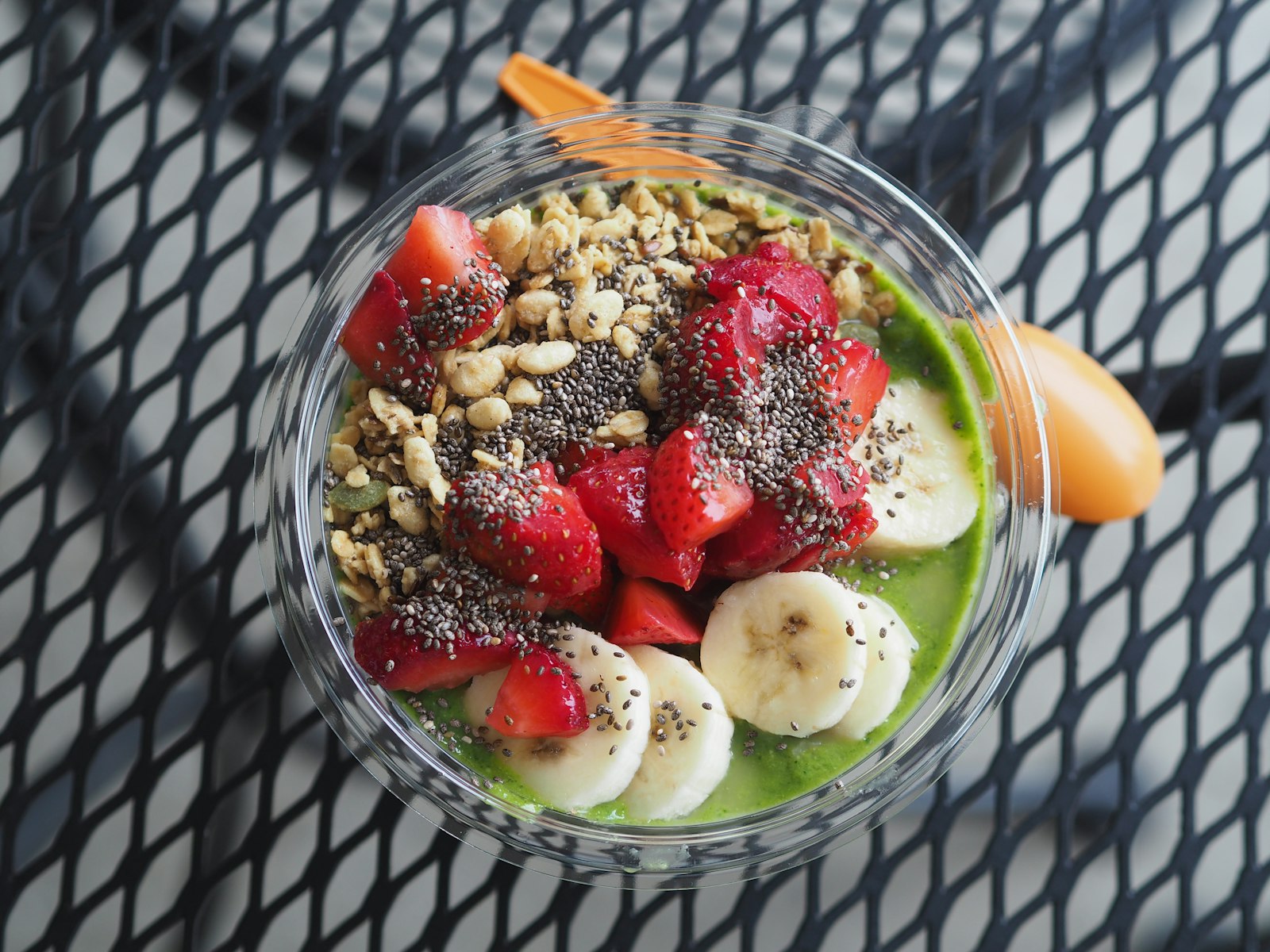 Green base topped with strawberries, banana, seeds and granola