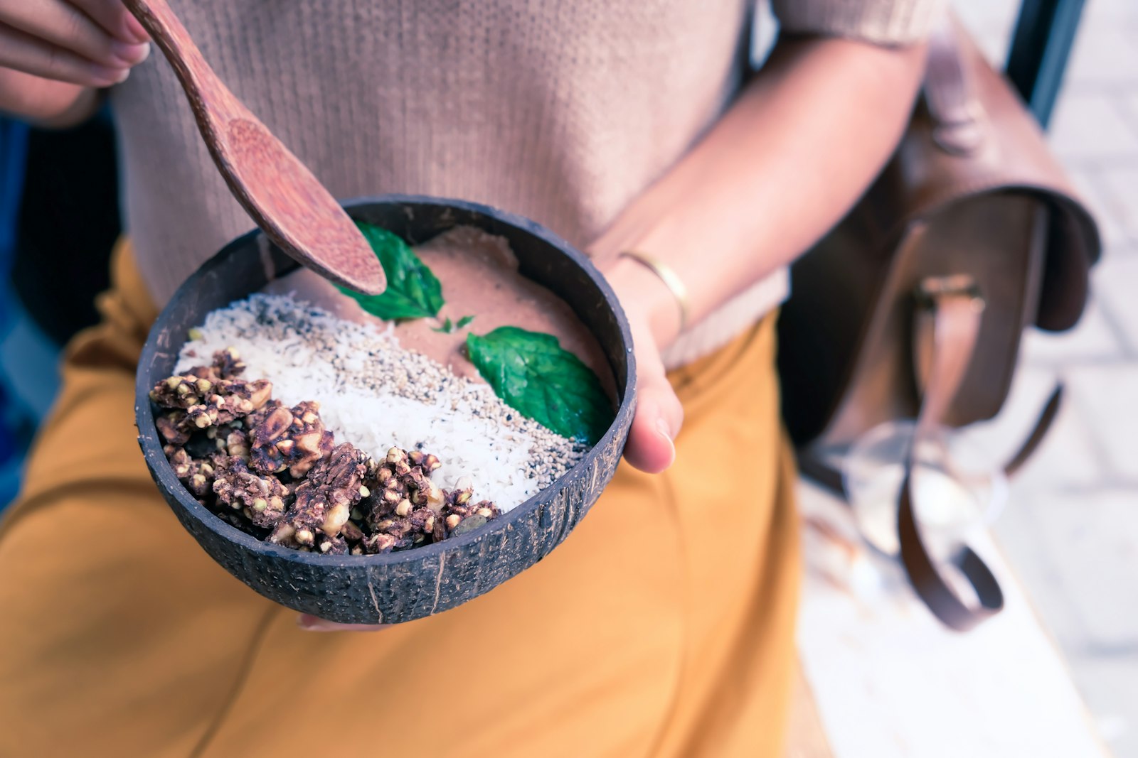 Hands holding a berry protein breakfast with coconut and granola