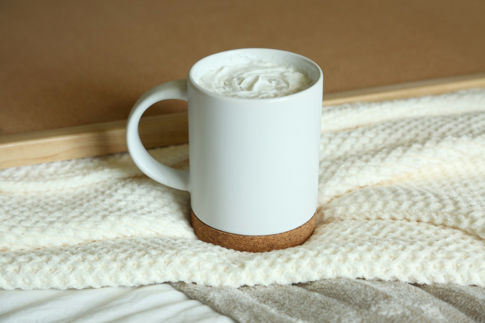 Warm milk in a white mug on a cozy blanket