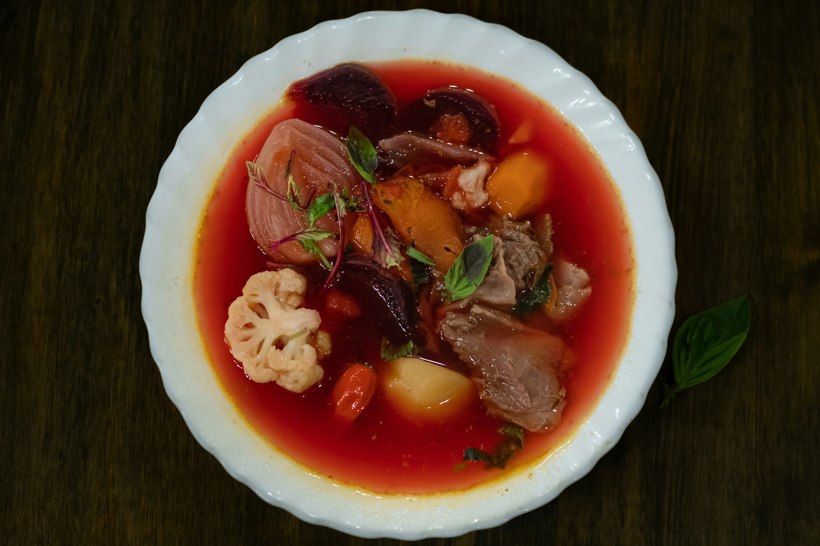 Bowl of ruby red borscht with vegetables and herbs