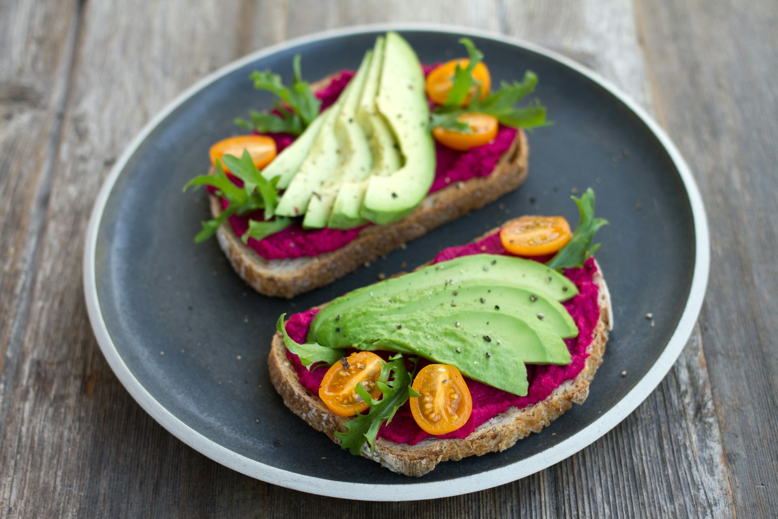 Toast topped with pink beet hummus, avocado and tomatoes