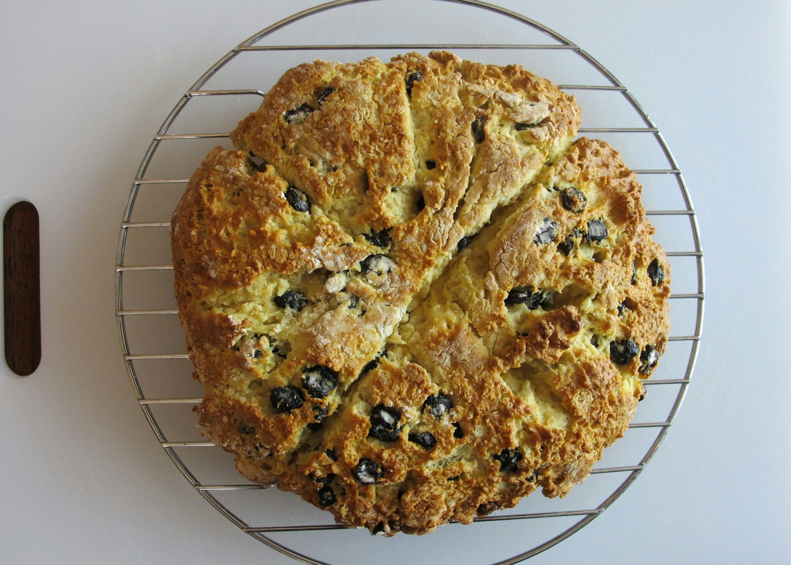 Round Irish soda bread with raisins on a cooling rack